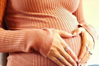 heart shaped hands over pregnant belly